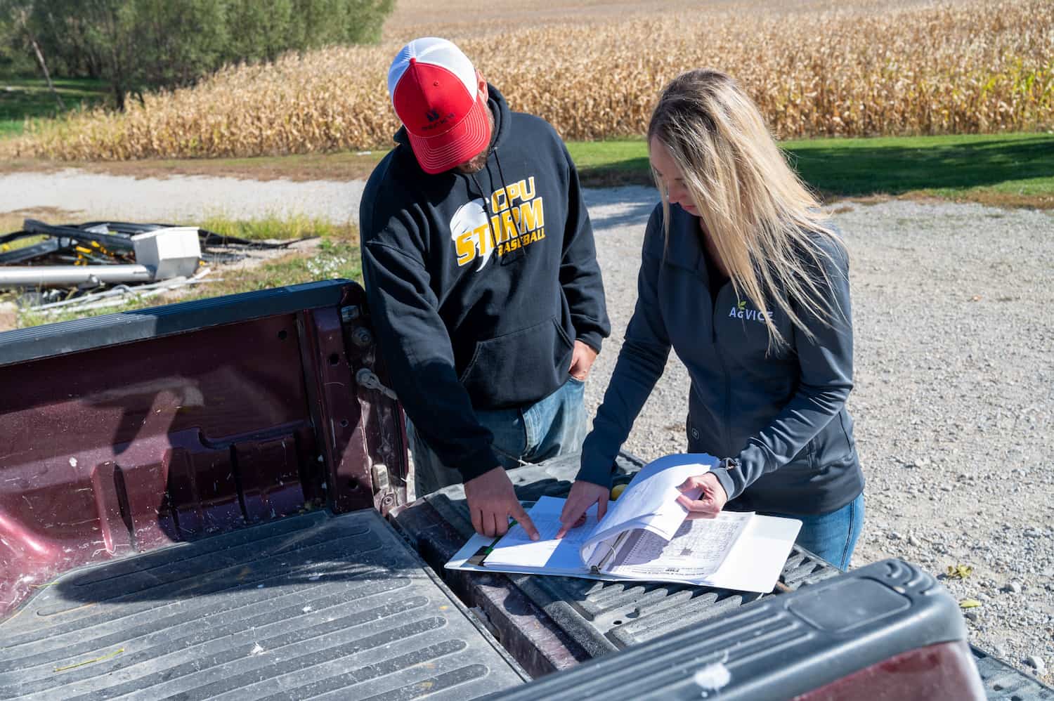 Pig farmers reviewing soil sample results on the back of a pickup.